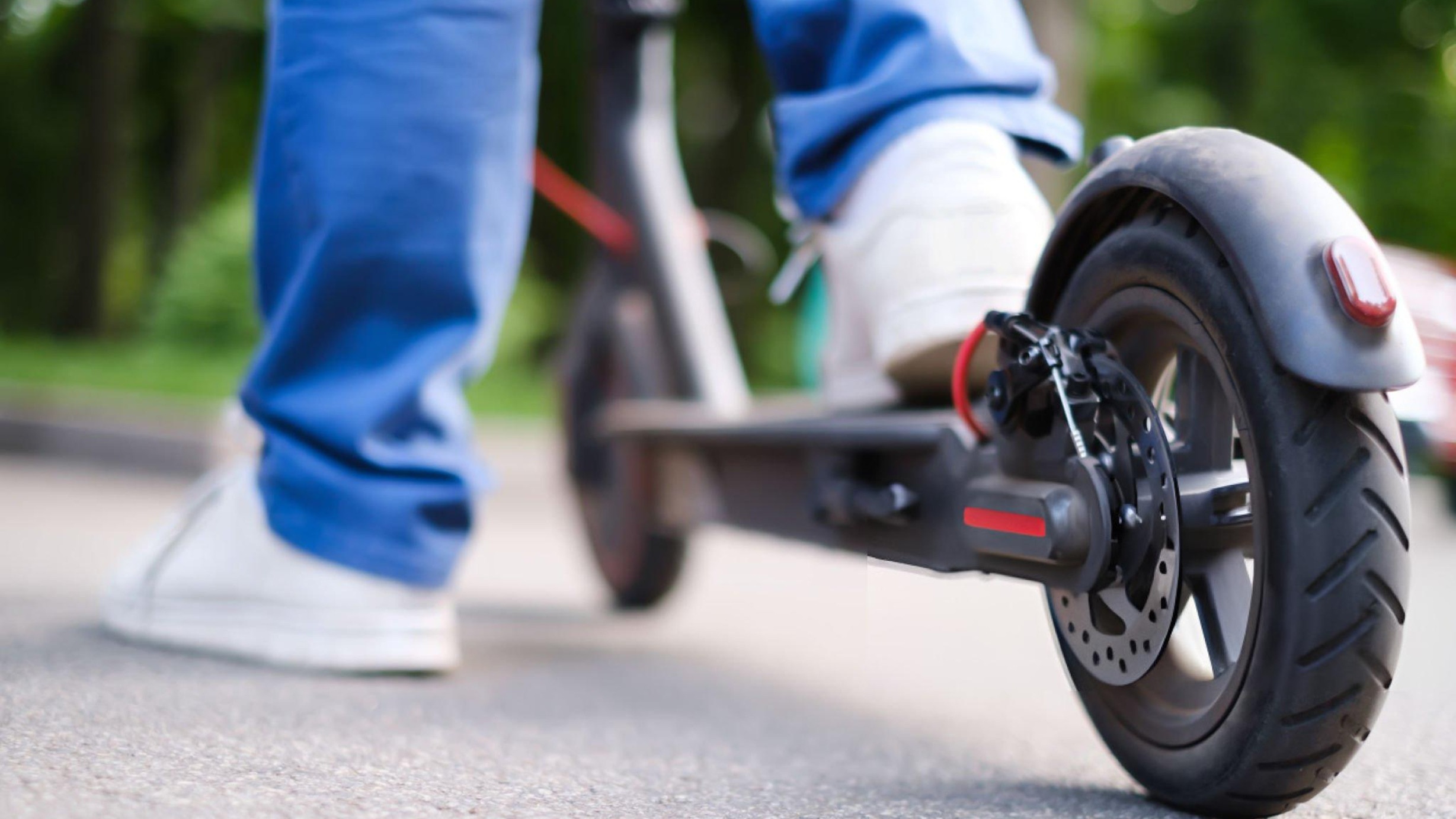 Hero image showing a brand‑neutral electric scooter and a rider’s hands holding a settings screen labeled Speed Limiter, with caution/legal icons in the background