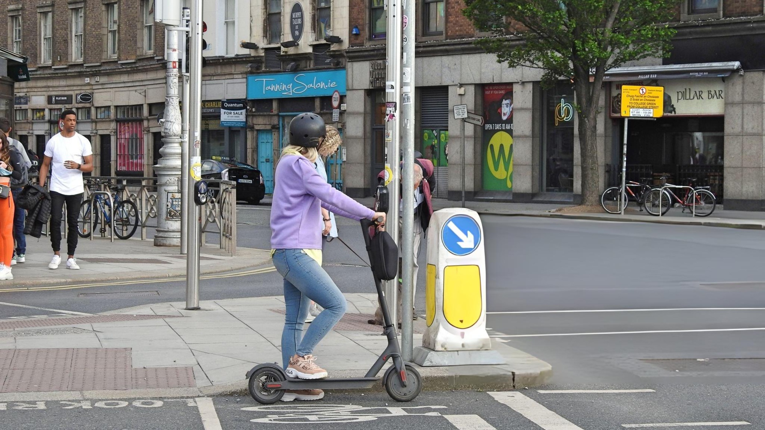 Electric scooter parked beside legal signpost showing various traffic regulations and laws